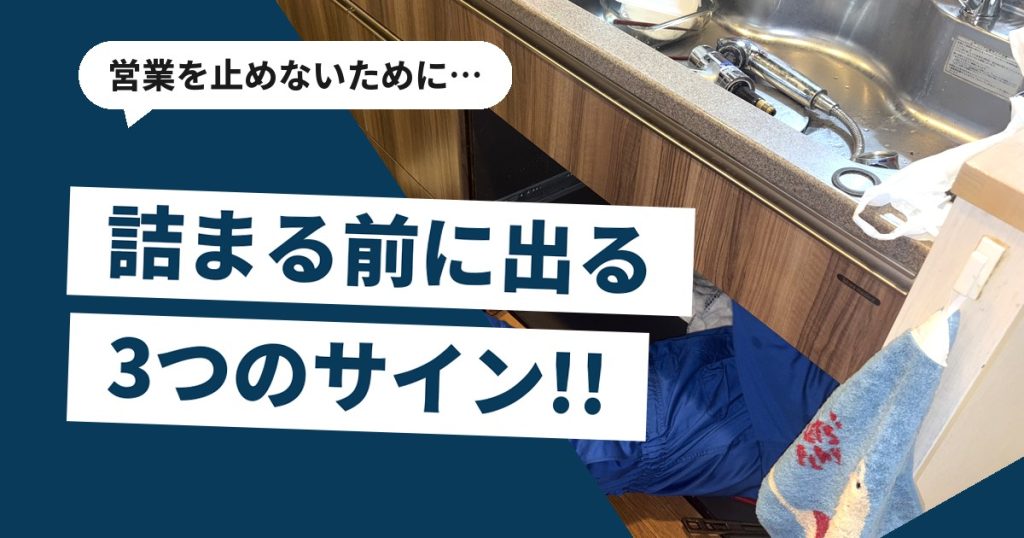 飲食店の厨房でシンク下の排水管を確認している作業の様子